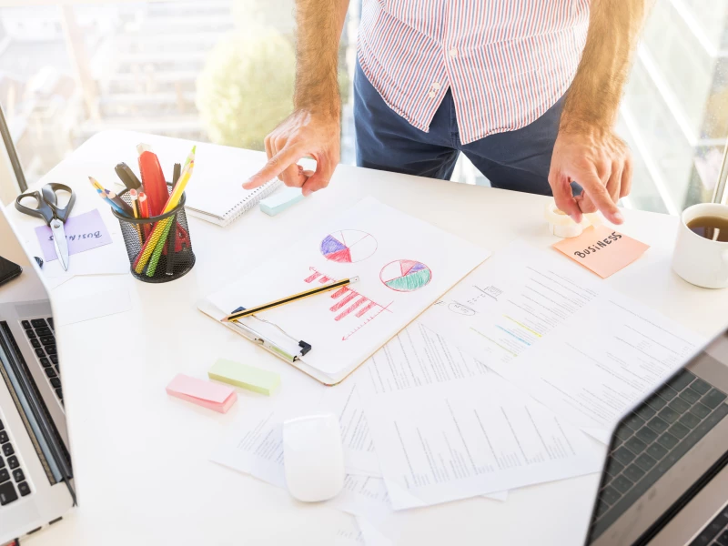 Iemand kijkt naar papierne met grafieken op een bureau, wat de uitkomsten zijn van Lean Scans