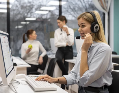 Medewerkster die met een headset op naar een computerscherm kijkt, om de sector Zakelijke Dienstverlening weer te geven